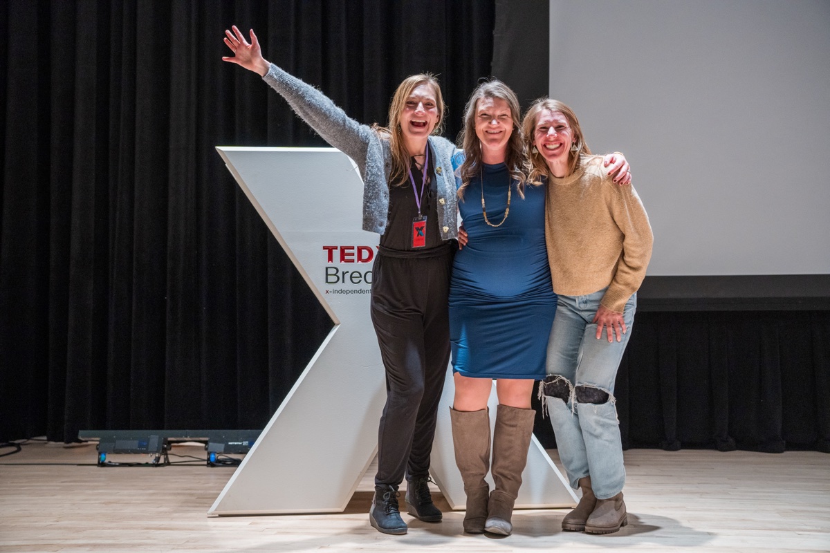 Three TEDxBreckenridge volunteers celebrating together on stage