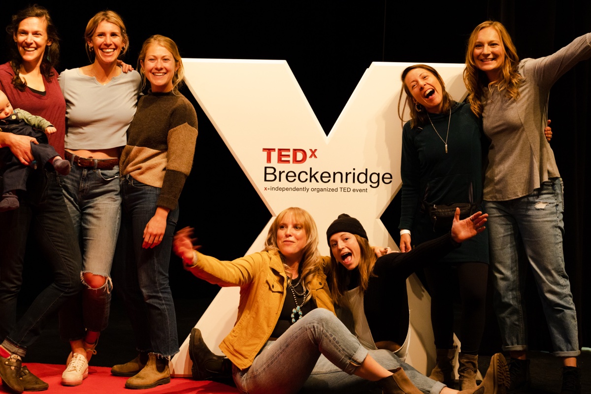 TEDxBreckenridge volunteer team members posing together in front of TEDx signage
